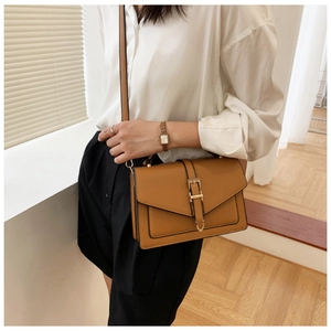 Close-up of a modern khaki brown rectangular shoulder bag with elegant gold buckle
