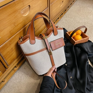 Canvas and brown leather bucket bag with top handle and crossbody strap for women