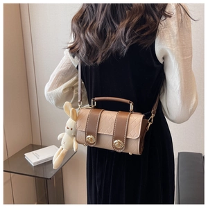 Close-up of quilted two-tone crossbody bag with elegant gold buckles and plush bunny charm