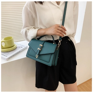 Detail of dark teal rectangular crossbody bag with elegant gold buckle and handle