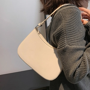 Minimalist beige leather underarm bag with adjustable strap shown on model's shoulder