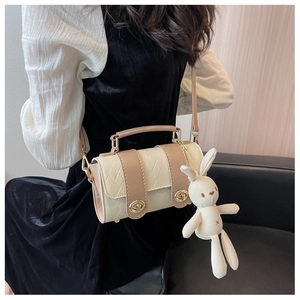 Detail of beige cylinder crossbody bag with quilted texture and cute rabbit charm decoration