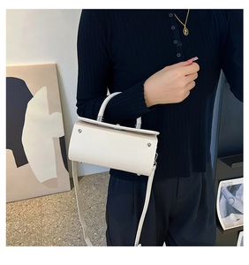 Minimalist beige crossbody bag with silver rivet detail shown in a lifestyle setting