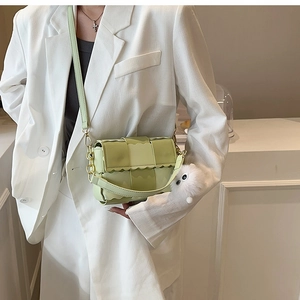 Light green woven crossbody bag with wavy edge detail and cute plush cat pendant