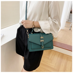 Detail of teal faux leather crossbody bag with vintage envelope flap and gold buckle