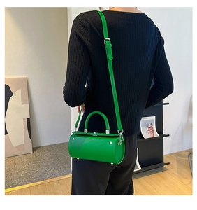 Green cylindrical leather crossbody bag styled with black ribbed knitwear for women