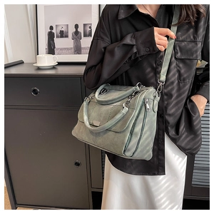 Detail view of the matte green leather texture and side zipper on this tote bag