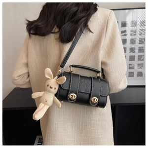 Detail of black quilted leather cylinder bag with gold locks and plush bunny charm