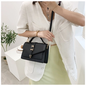 Close-up of black structured crossbody bag with gold buckle and stylish top handle
