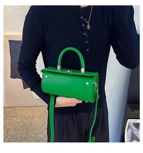 Close-up of vibrant green cylinder handbag with silver hardware and smooth texture