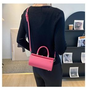 Chic magenta square handbag with silver rivets and sleek top handle in modern room
