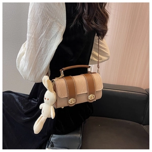 Detail of cylinder beige shoulder bag with brown accents and white rabbit charm
