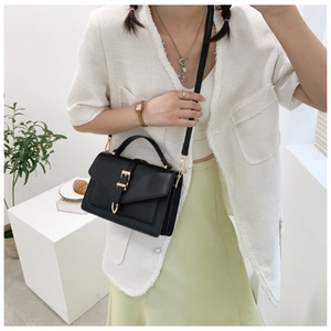 Chic black crossbody bag with gold buckle hardware and fine leather texture on model
