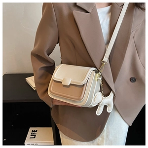 Chic two-tone flap crossbody bag with a cute puppy pendant shown on a model