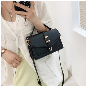 Detailed close-up of a black textured leather crossbody bag with a golden buckle closure