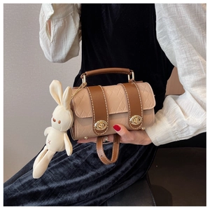 Detail of beige and brown quilted cylinder bag with dual gold twist locks and plush charm