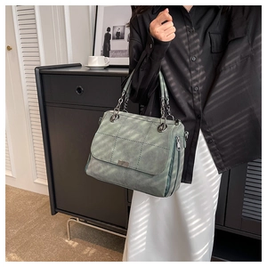 Close-up of matte quilted green tote bag featuring silver chain handle and square metal buckle