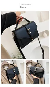 Detail of black structured crossbody bag with gold buckle and top handle styling