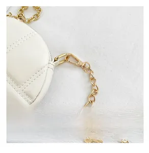 Détail de près du sac en cuir matelassé blanc avec des anneaux de chaîne en métal doré