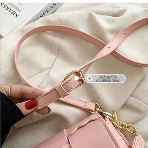 Detail of adjustable pink faux leather shoulder strap with gold metal buckle and chain hook