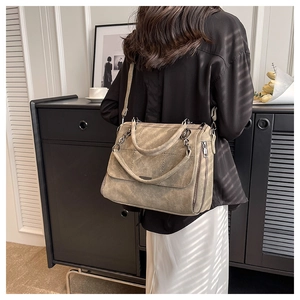 Model wearing a large taupe matte tote bag with round handles and long shoulder strap