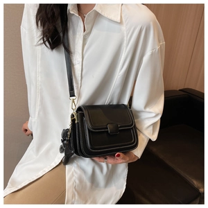 Chic black crossbody bag with white contrast stitching and a cute bear charm pendant