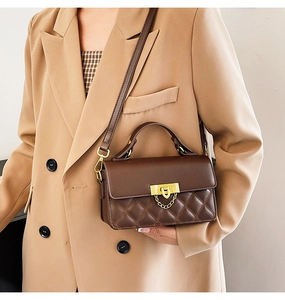 Detail der dunkelbraunen gesteppten Ledertasche mit goldenem Drehverschluss und Griff