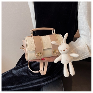 Detail of a cylindrical cream and beige quilted bag featuring a cute white bunny charm