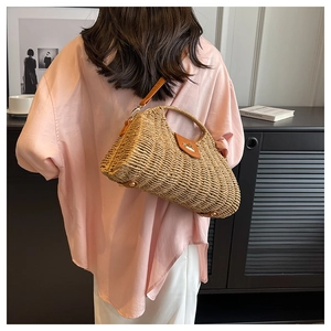 Detail der handgewebten Stroh-Hobo-Tasche mit brauner Lederklappe und goldenem V-Verschluss