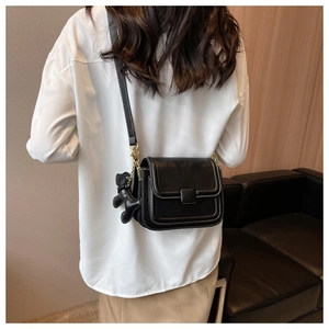 Detail of black leather crossbody bag with white contrast stitching and cute animal charm