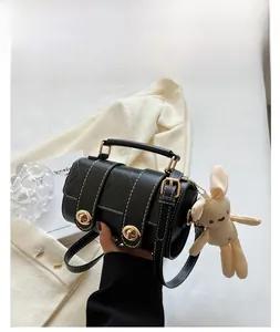Detail of black quilted barrel bag with gold locks and a cute bunny plush charm