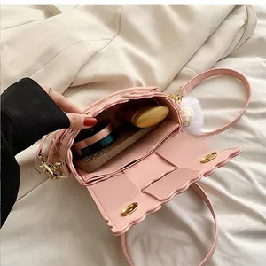 Detail view of pink woven crossbody bag interior holding phone, lipstick and compact powder