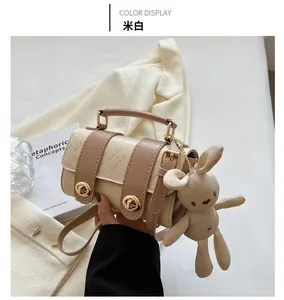 Detail of off-white and brown patchwork handbag with gold locks and rabbit pendant