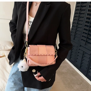 Detail of pink woven PU leather shoulder bag with gold chain and plush bunny charm