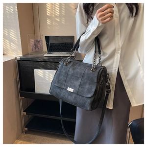 Detail of grey matte quilted tote bag with chain strap and metallic brand plate