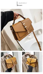 Detail of brown leather crossbody bag with gold buckle and top handle in studio setting