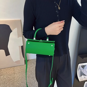 Modern bright green leather box handbag with round handle and silver protective feet