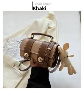 Detail of khaki quilted cylinder bag with dual brown buckles and a cute rabbit charm