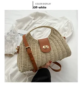 Details der beigefarbenen Strohhandtasche mit braunem Lederriemen und Goldverschluss
