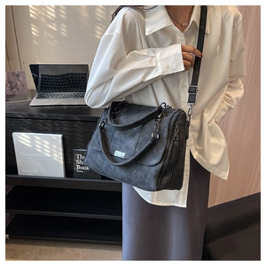Detail of dark grey frosted leather tote bag with metallic plate and dual handles