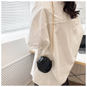 Gros plan du mini sac rond matelassé noir avec bandoulière chaîne sur un modèle
