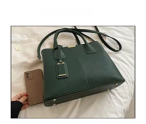 Detailed view of dark green lychee textured handbag next to a smartphone for size reference