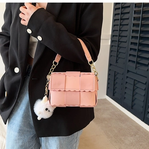 Pink woven crossbody bag with wavy edge detail and cute white plush ball pendant