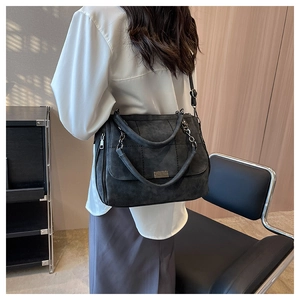 Detail of dark grey frosted tote bag featuring quilted stitching and metal chain strap