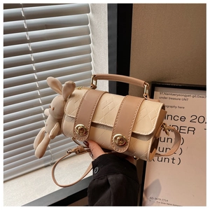 Detail of cream beige leather barrel bag with quilted patterns and plush rabbit charm