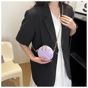 Mini sac rond matelassé violet avec bandoulière chaîne dorée porté par un mannequin