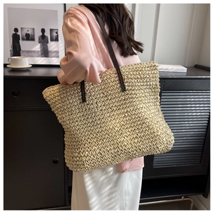 Detail of woven straw tote bag with leather shoulder straps and textured surface