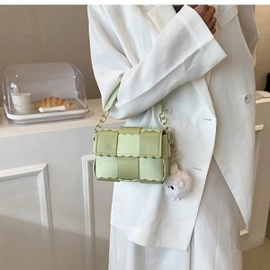 Detail of mint green woven crossbody bag with wavy edges and cute plush charm