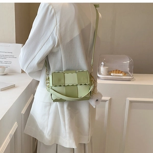 Detail of light green woven bag with scalloped edges and gold chain accessory