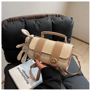 Detail of beige quilted faux leather bag with gold clasp and plush bunny keychain